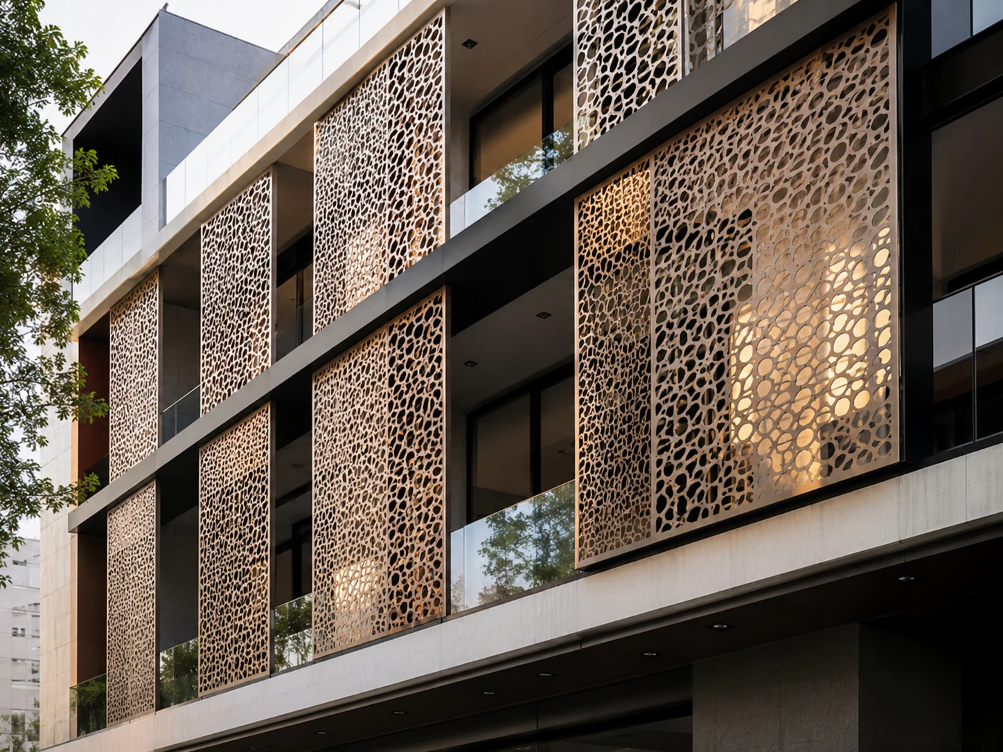 Fațadă de clădire cu panouri metalice perforate decorative montate în dreptul ferestrelor, luminate seara